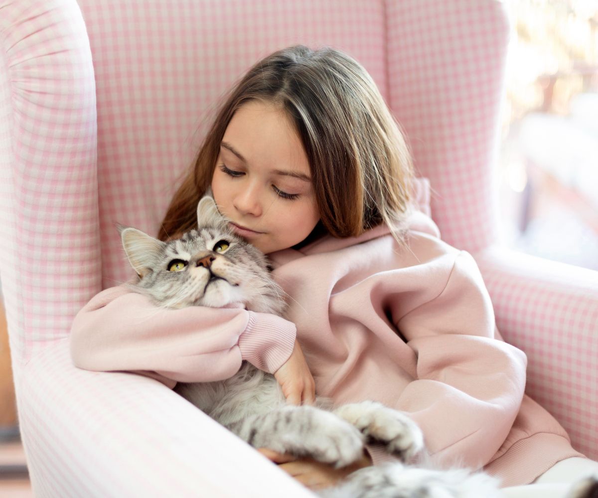 girl hugging cat pink chair