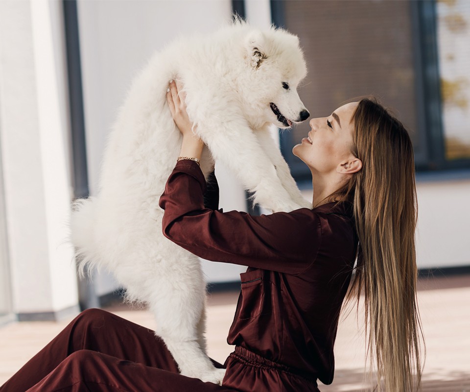 woman holding white puppy
